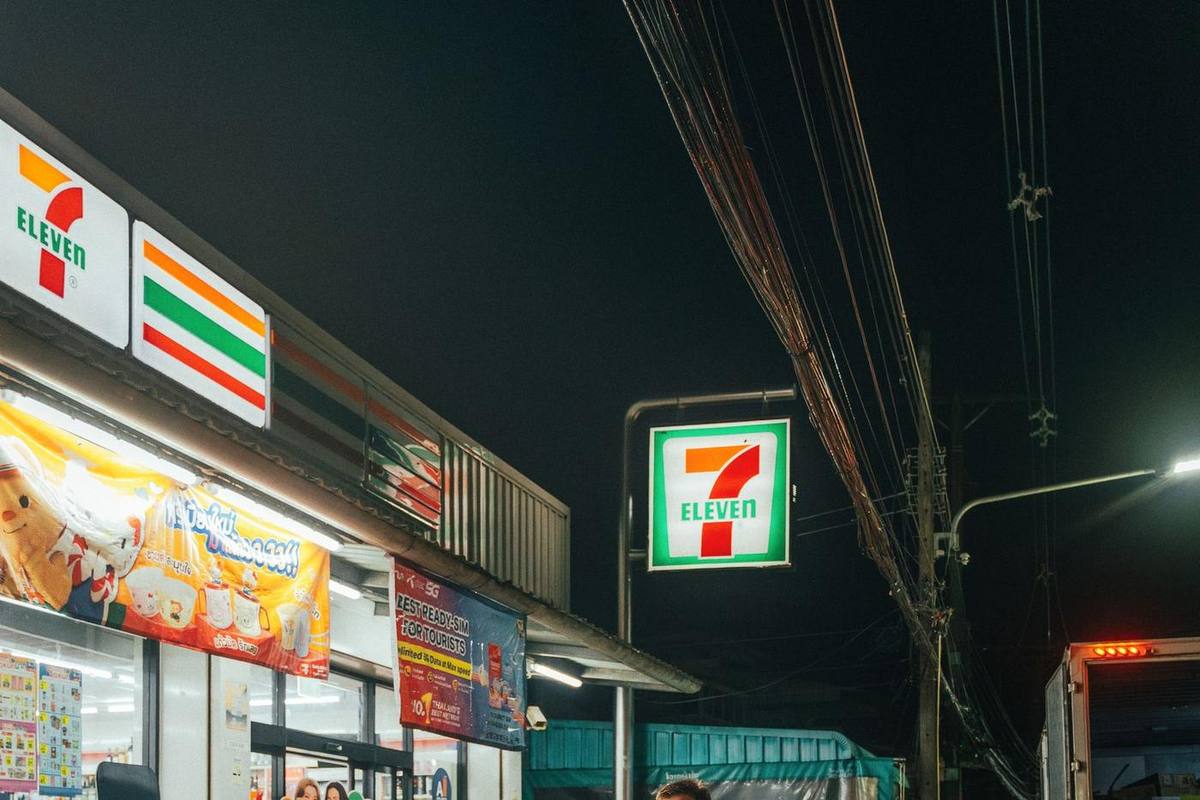 A 7-Eleven shop and its glowing sign on a street in Phuket at night