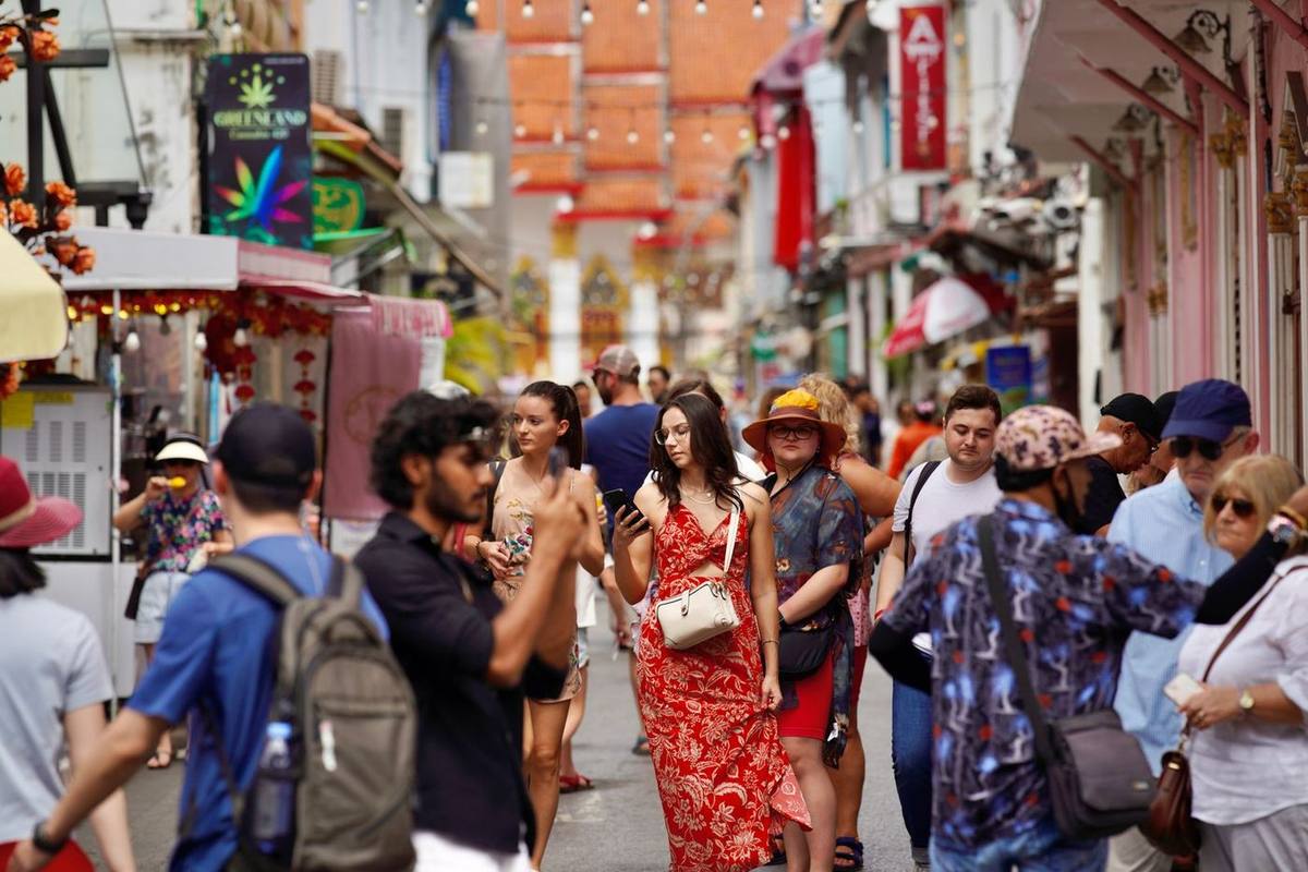 Tourists walking down a busy, colourful street in Phuket, Thailand